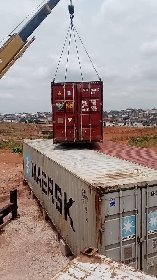 Crane lifting a shipping container into place on site